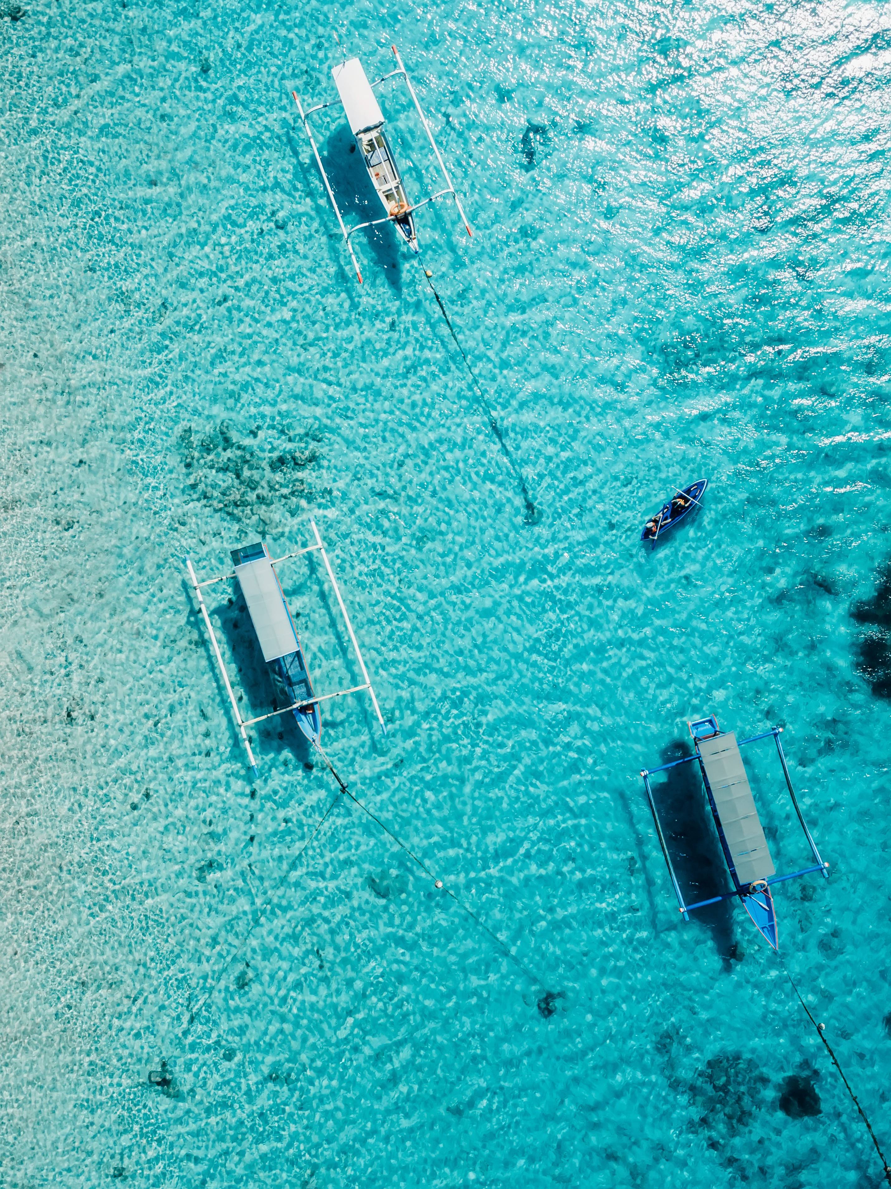 Aerial of outrigger boats on crystal-clear Bali waters