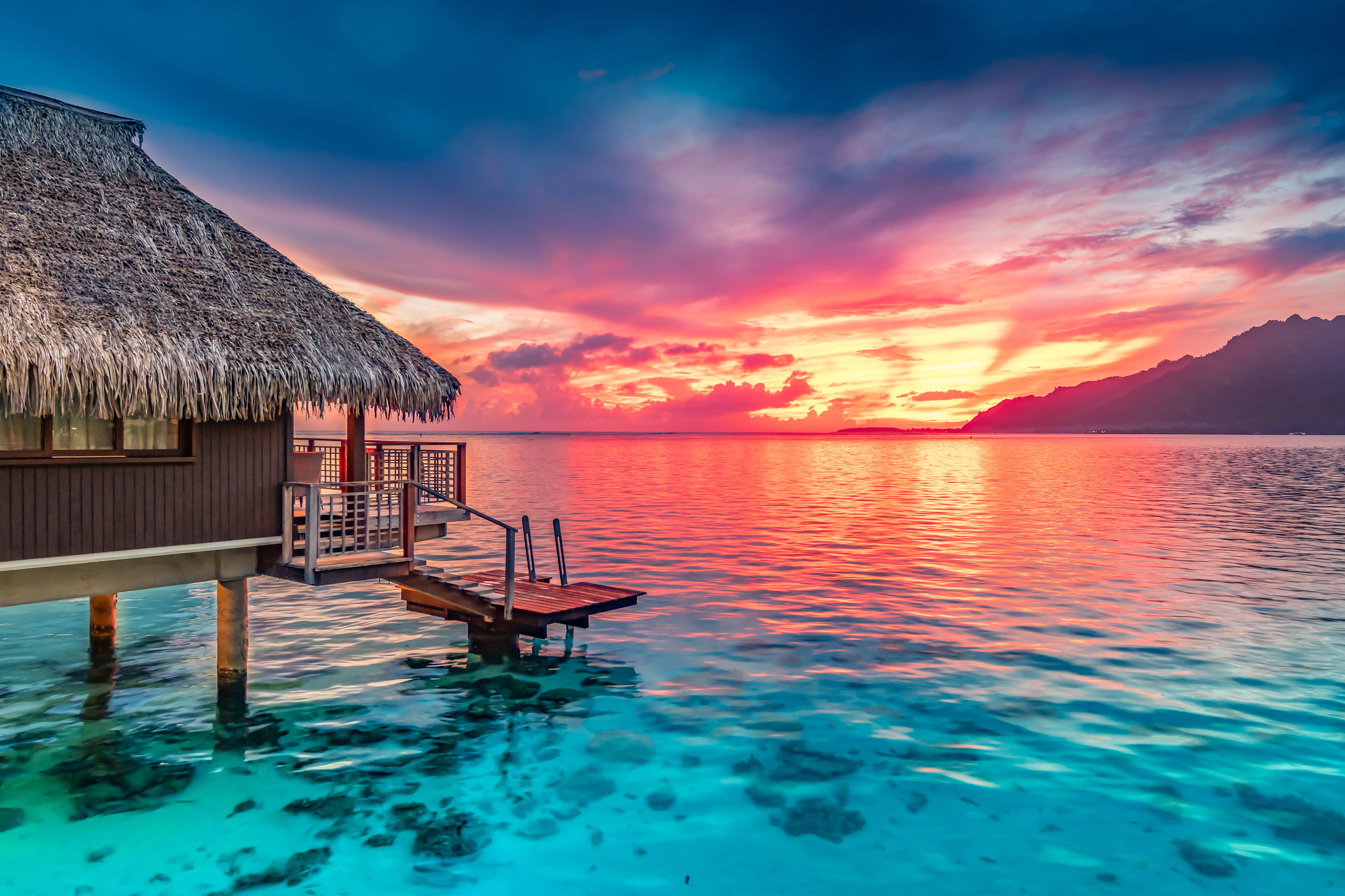 Luxury overwater bungalow at sunset in tropical paradise