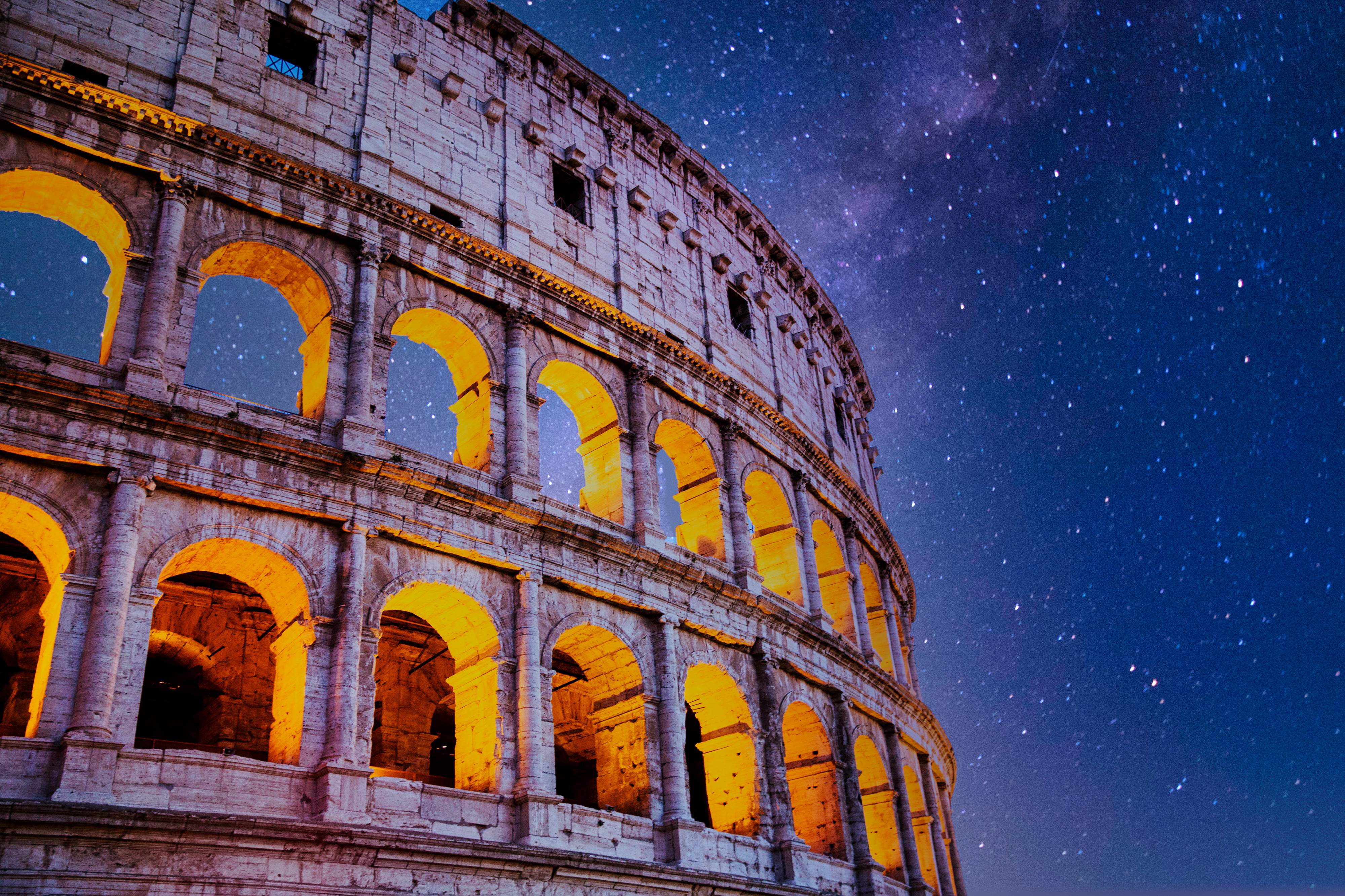 Rome Colosseum illuminated at night under starry sky