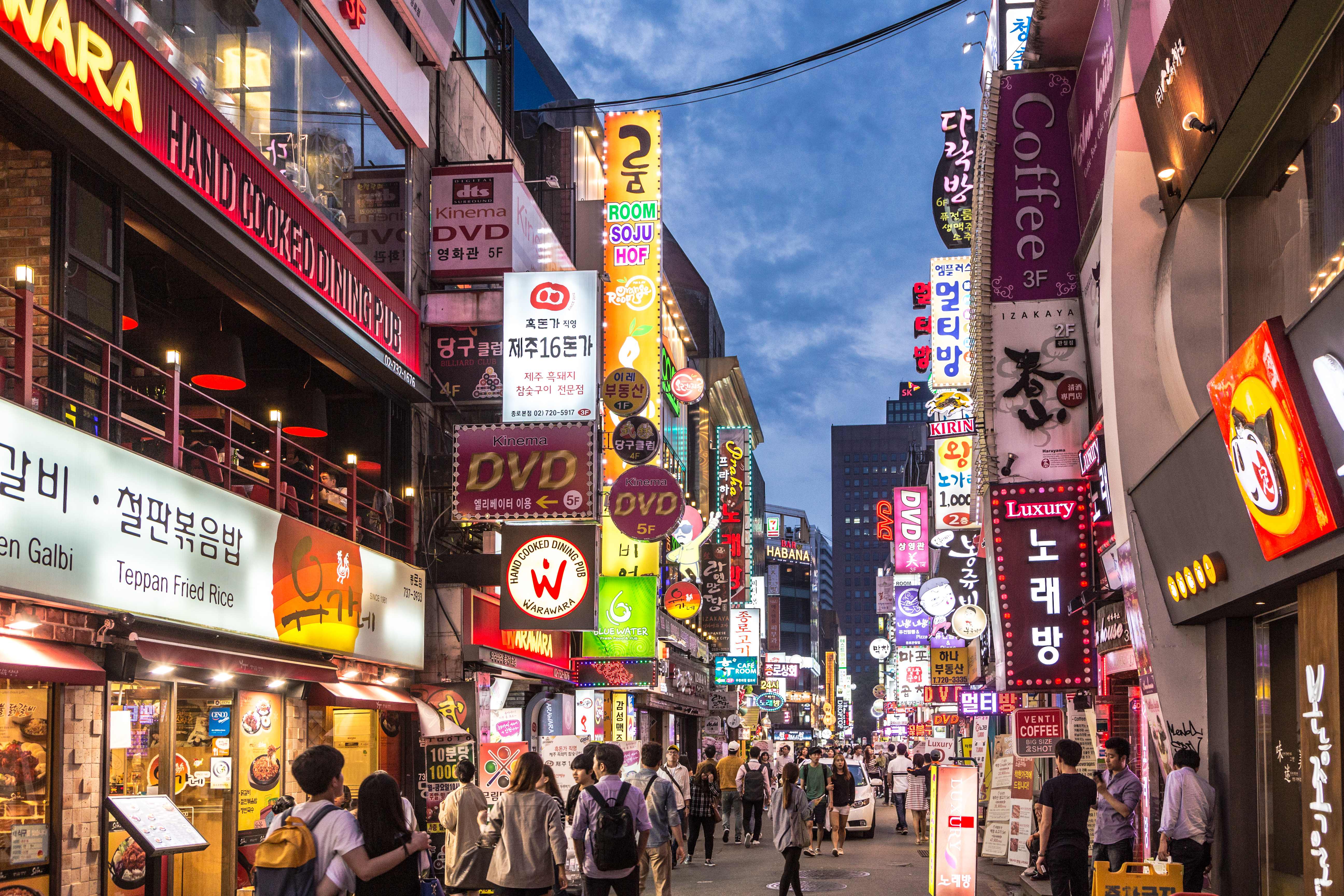 Bustling Seoul street at night with neon signs and crowds